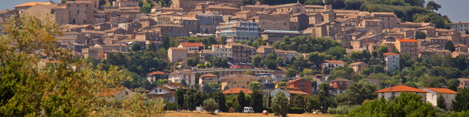A historic town with a prominent church and tower, surrounded by lush greenery and rolling hills.
