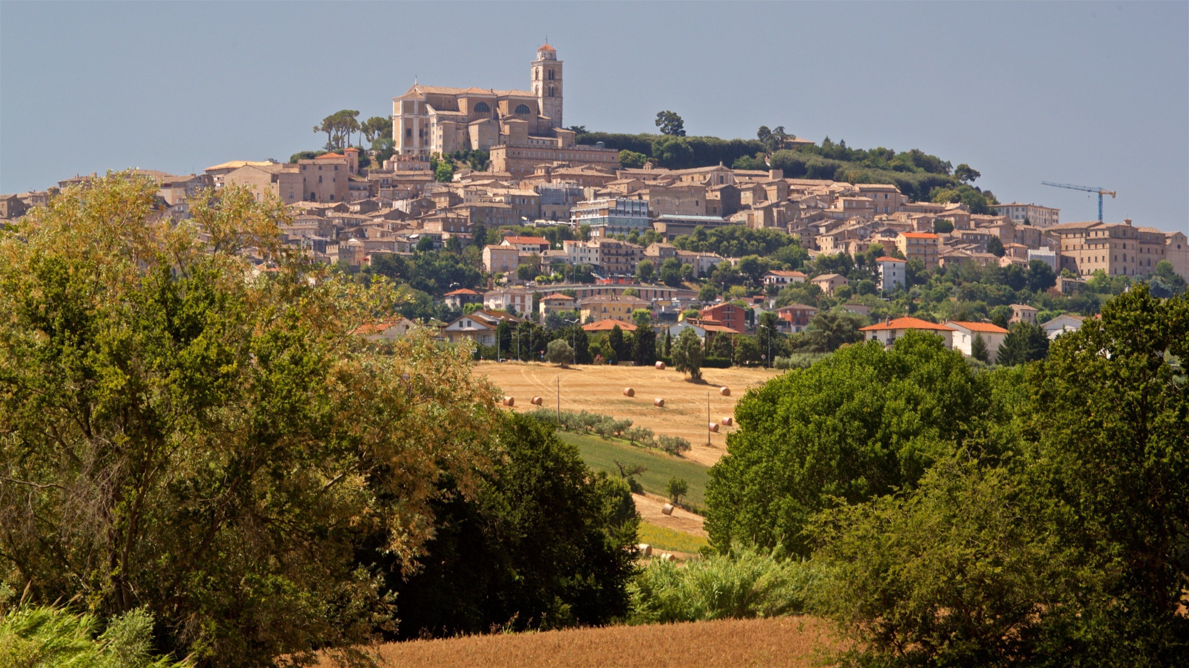 A historic town with a prominent church and tower on a hill, surrounded by lush greenery and agricultural fields.