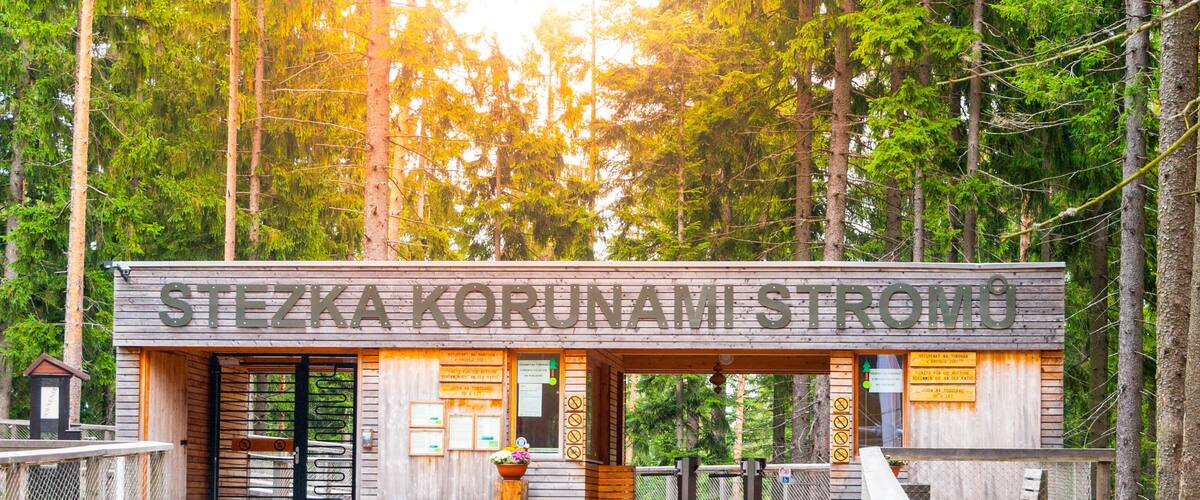 Un bâtiment en bois avec une enseigne indiquant « STEZKA KORUNAMI STROMO », situé dans une zone boisée.