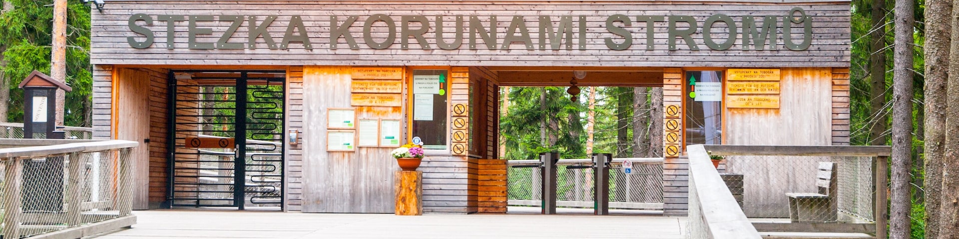 A wooden building with a sign reading "STEZKA KORUNAMI STROMO" in a forested area.