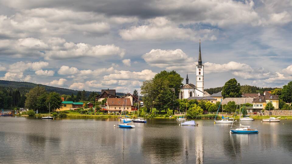 A lake with boats, a church, and houses along the shore.