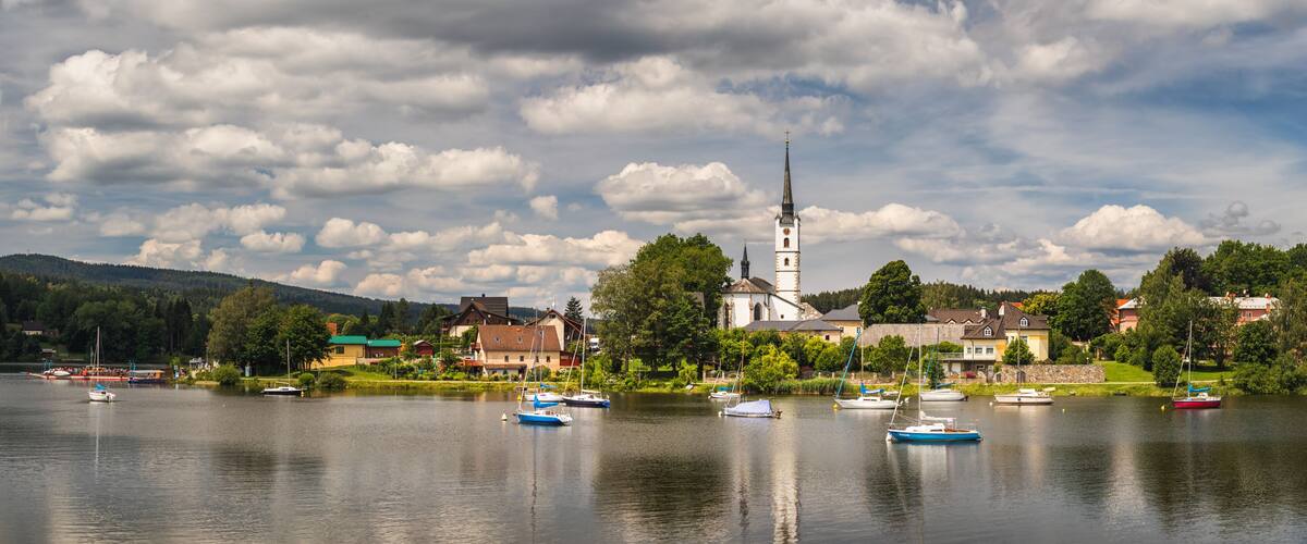 A lake with boats, a church, and houses along the shore.