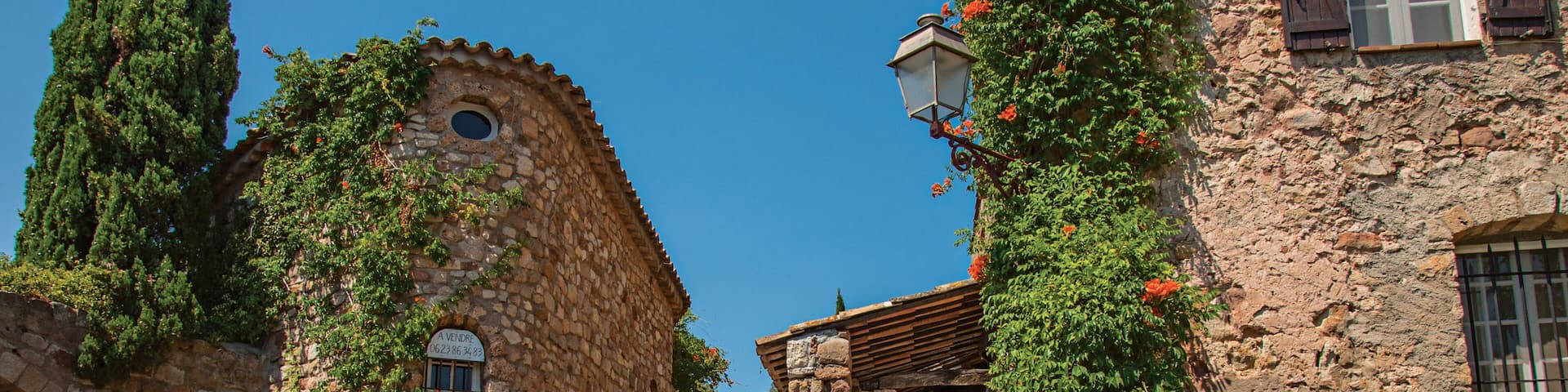 Old stone houses in alley under blue sky, at the gorgeous medieval hamlet of Les Arcs-sur-Argens. Provence region, Var department, southeastern France.