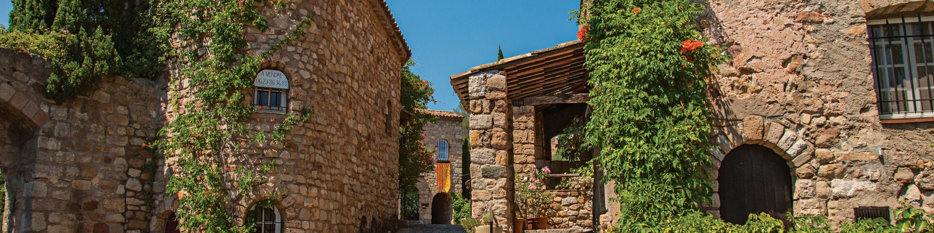 Old stone houses in alley under blue sky, at the gorgeous medieval hamlet of Les Arcs-sur-Argens. Provence region, Var department, southeastern France.
