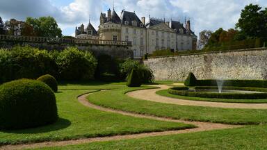 Un magnifique château doté d’un jardin à la française, avec des haies soigneusement taillées et une fontaine.