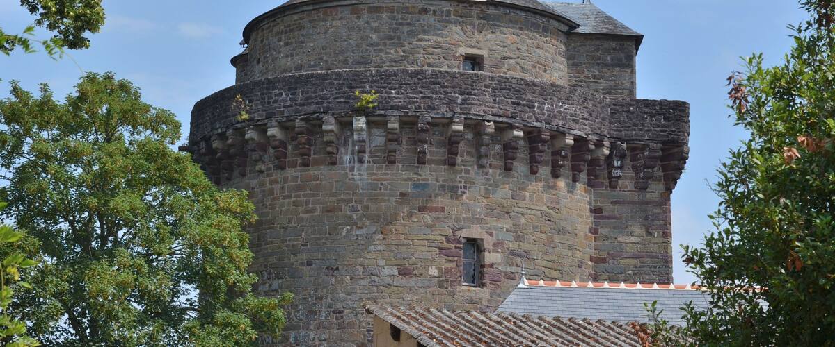A historic stone tower with a conical roof and a flag on top.