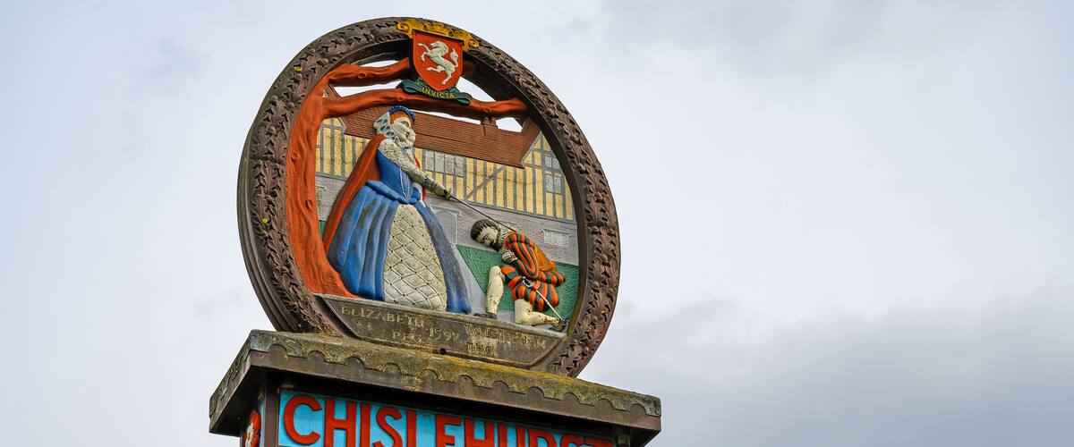A historical sign with a coat of arms and the name 'CHISLEHURST'.