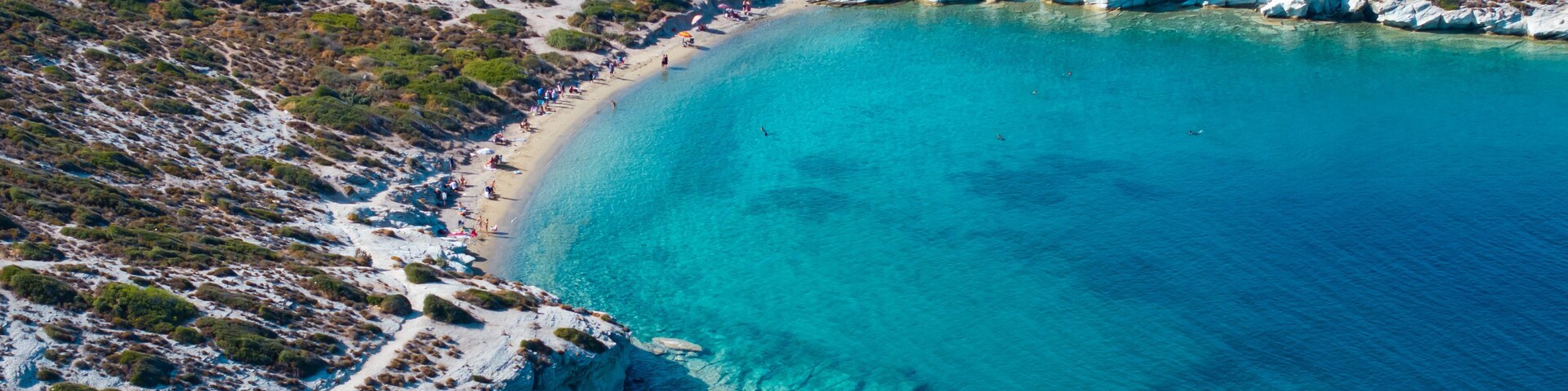 Un paisaje costero con un mar turquesa cristalino, acantilados rocosos y vegetación escasa.