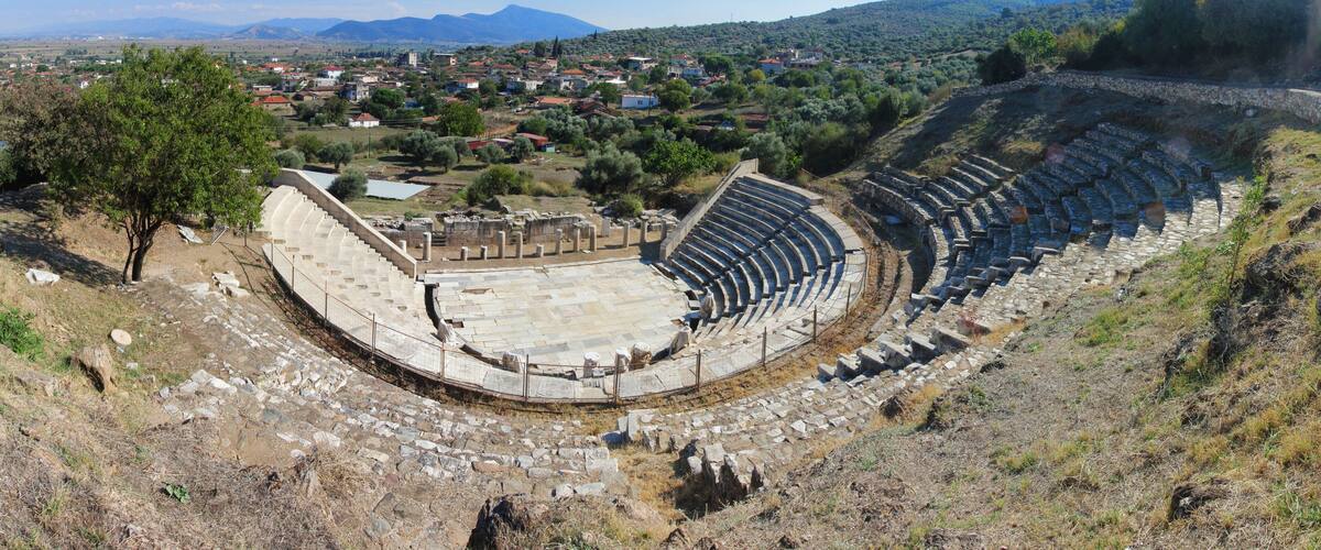 An ancient amphitheater surrounded by hills and a small town.