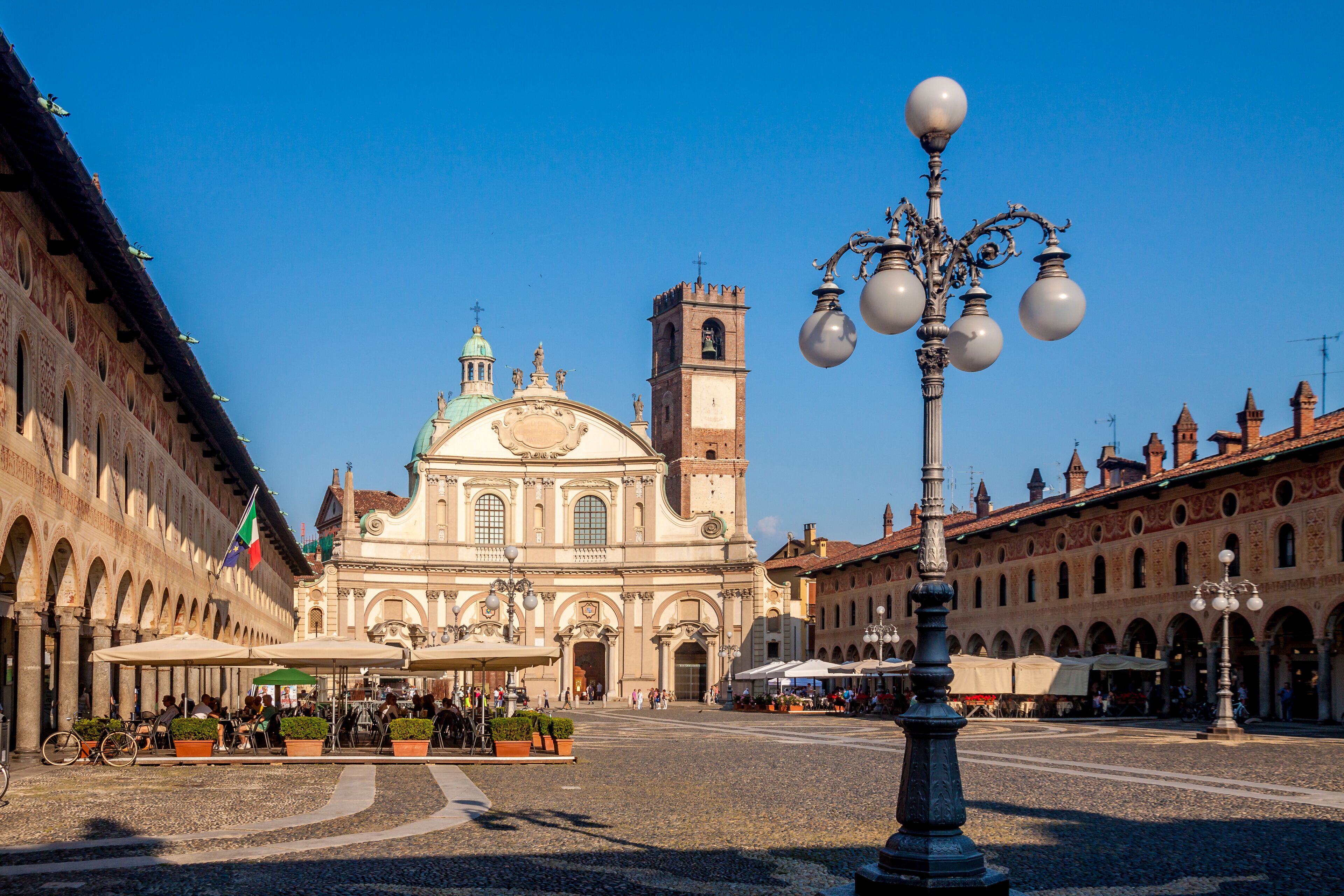 A historic square with a prominent church, a clock tower, and a decorative street lamp.