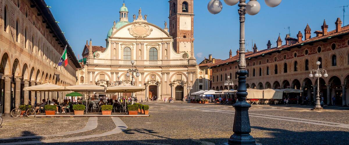 A historic square with a prominent church, a clock tower, and a decorative street lamp.