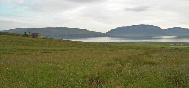 Fields and farmhouse with Clestrain Sound in background Hills in distant background are the Island of Hoy. Photograph is taken on the Orkney Mainland.