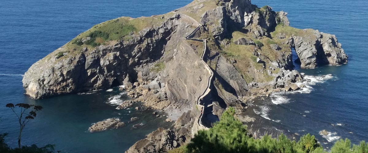 A rocky island with a building on top and a winding path leading to it.
