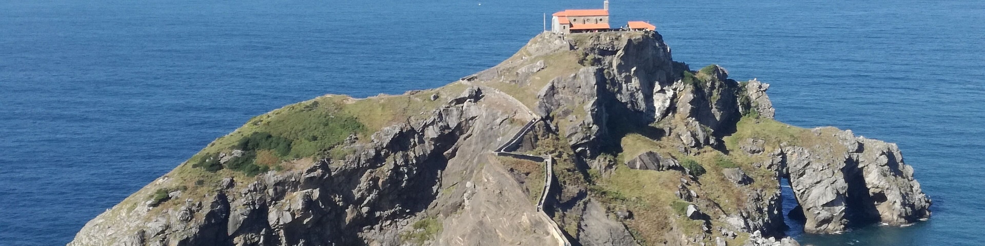 Una isla rocosa con un edificio en la cima y un camino sinuoso que lleva a él.