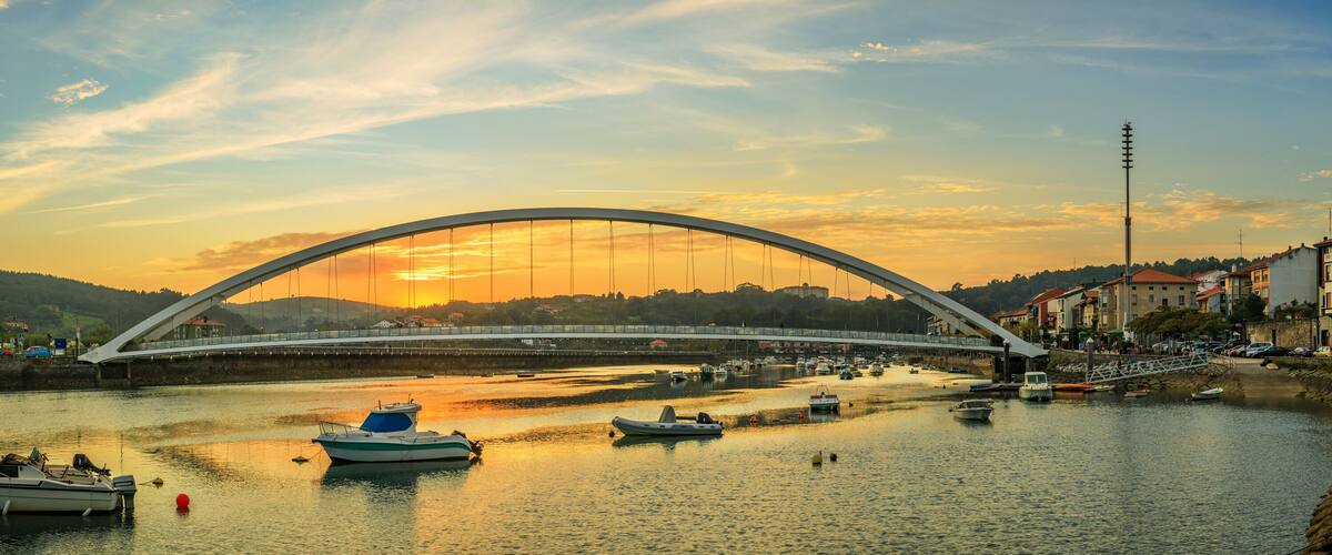 A river with boats, a bridge, and buildings along the shore.