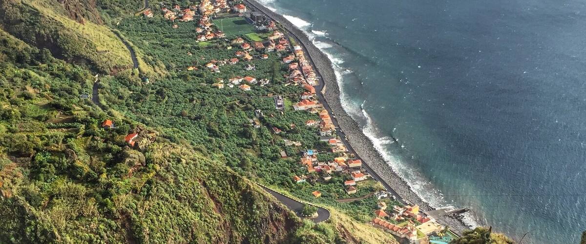 A coastal town nestled between green hills and the ocean.