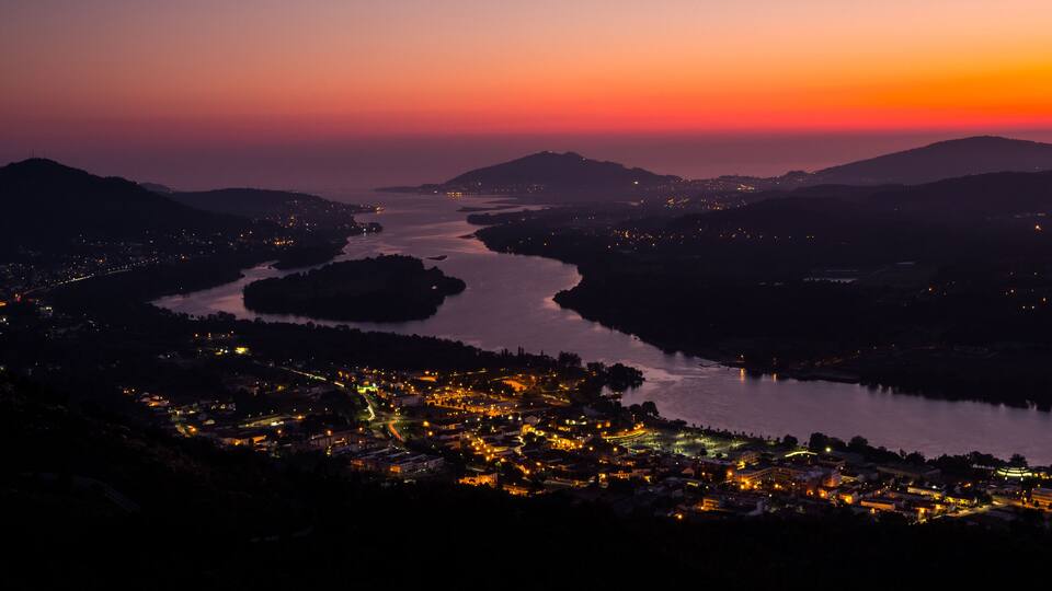 A river winding through a valley with a town on its banks, surrounded by hills.