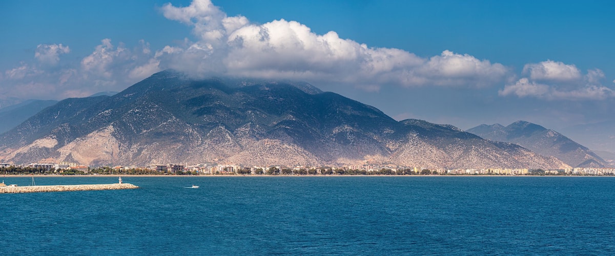 A coastal city with a prominent mountain range in the background.