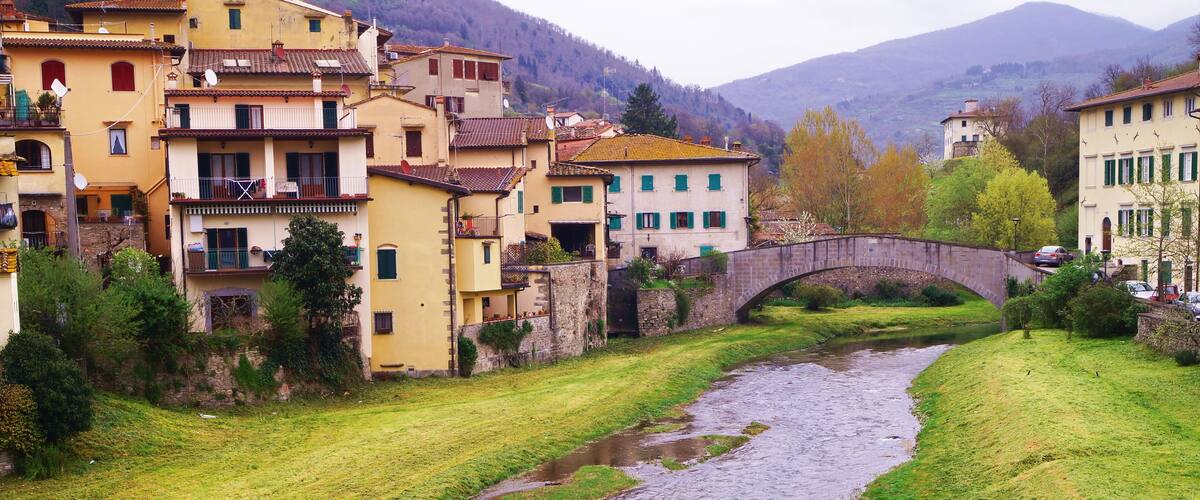 A river flowing through a town with buildings and a stone bridge.