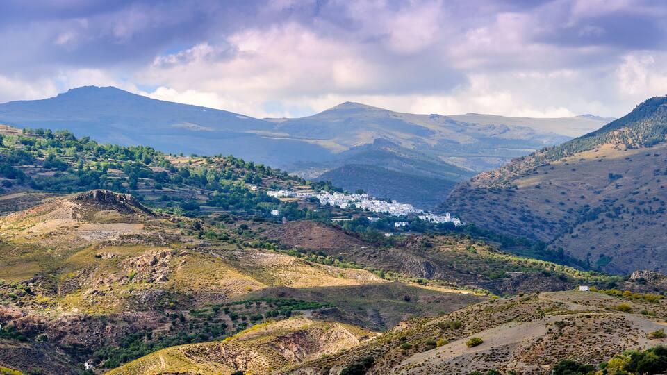 A mountainous landscape with a village nestled among rolling hills.