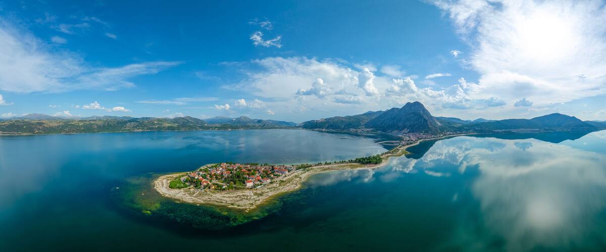 A coastal town with a mountain in the background and a clear sky.