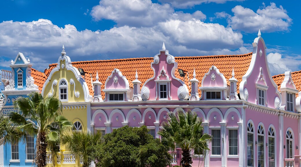 A wide panoramic shot of colorful pink yellow and blue Dutch colonial style architectural facades in downtown Oranjestad Aruba Caribbean vacation destination