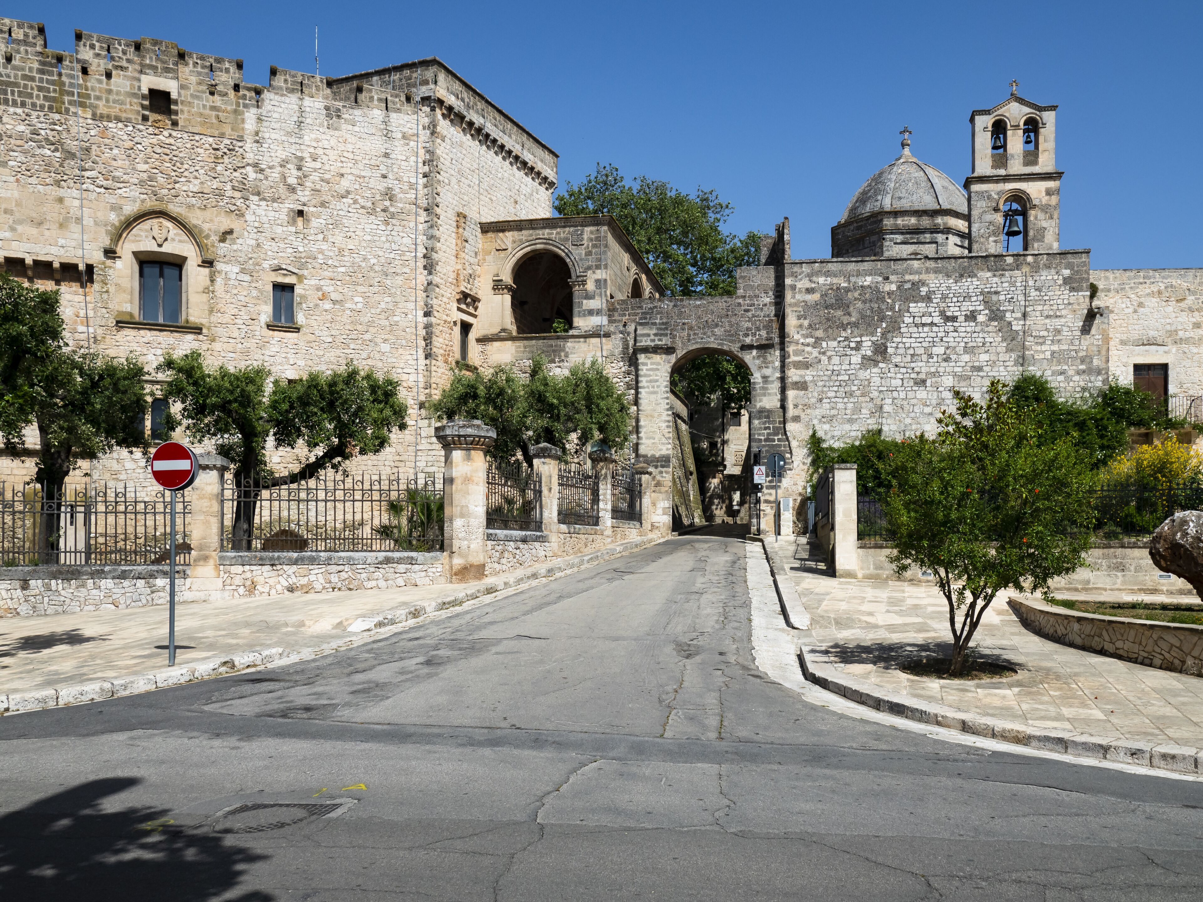 A stone gate leading to a historic building with a bell tower.