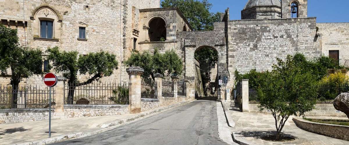 A stone gate leading to a historic building with a bell tower.