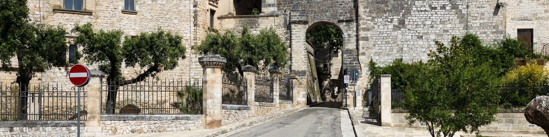 A stone gate leading to a historic building with a bell tower.