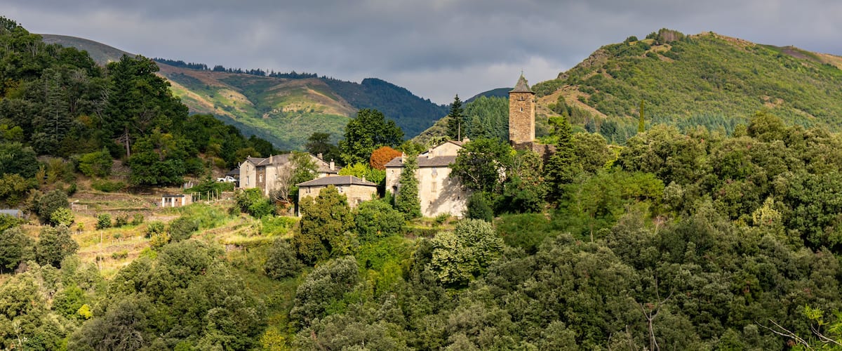 A village with stone houses and a tower on a hillside.
