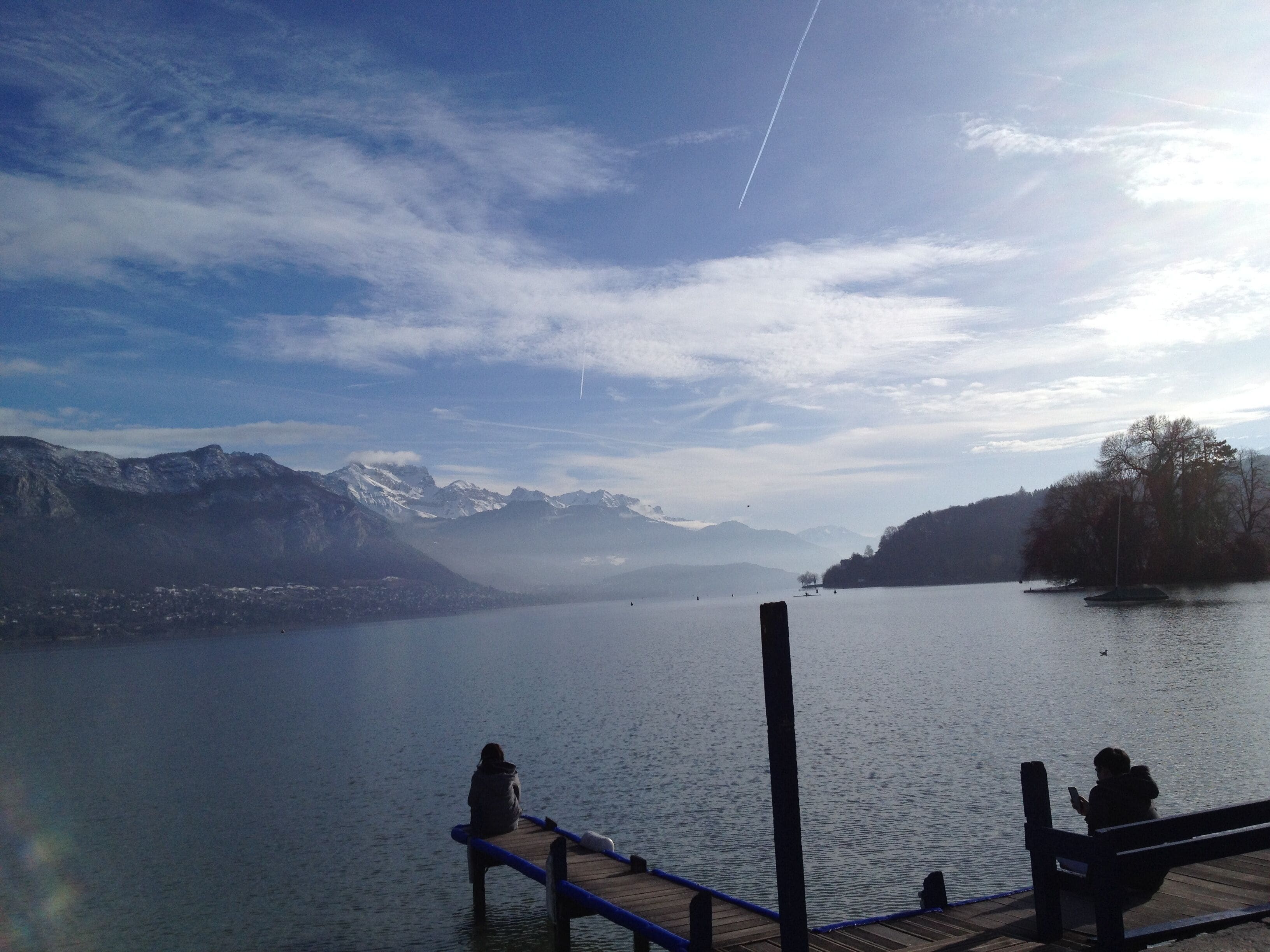 A calm lake with mountains in the background and a clear sky.