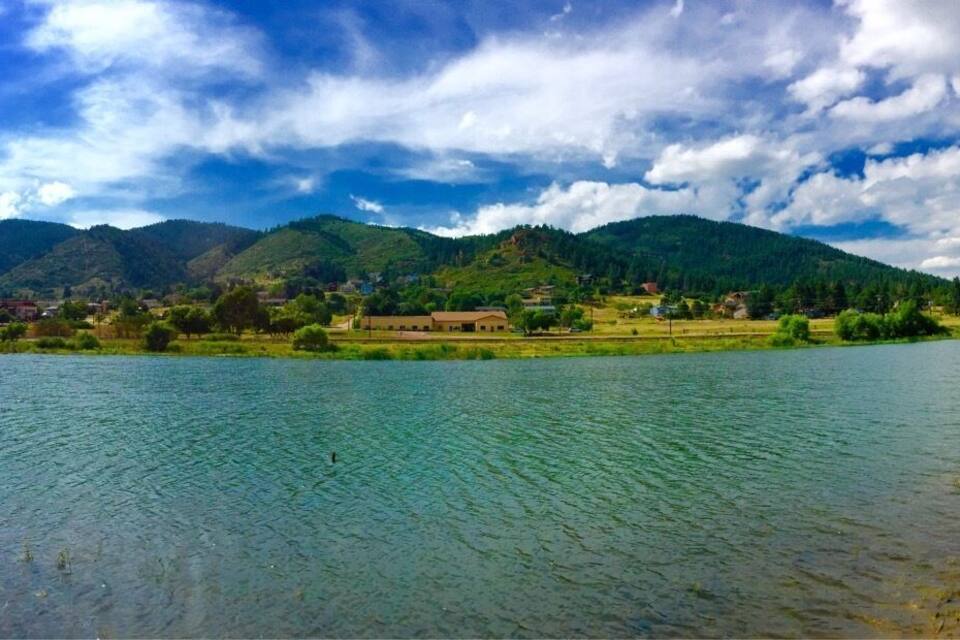 A river with mountains in the background, a clear sky, and a small building near the water.