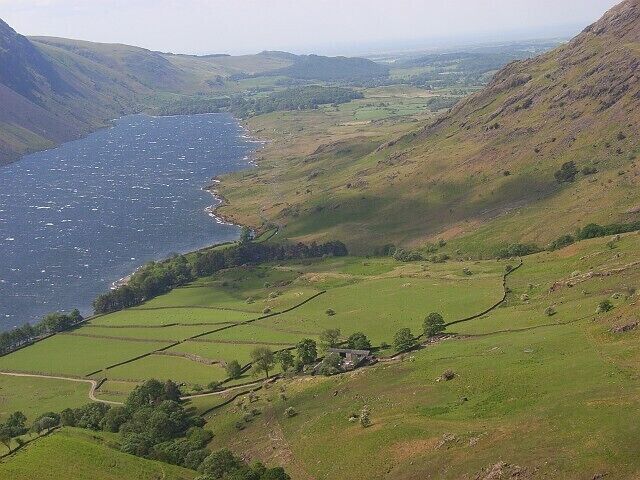 A coastal landscape with a river, green fields, and rolling hills.
