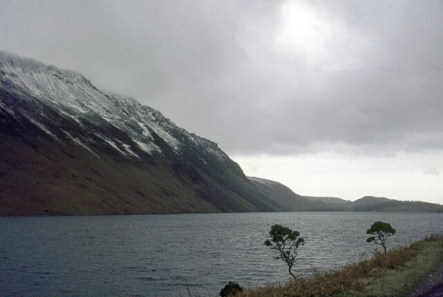A lake with a mountain in the background and a few trees in the foreground.