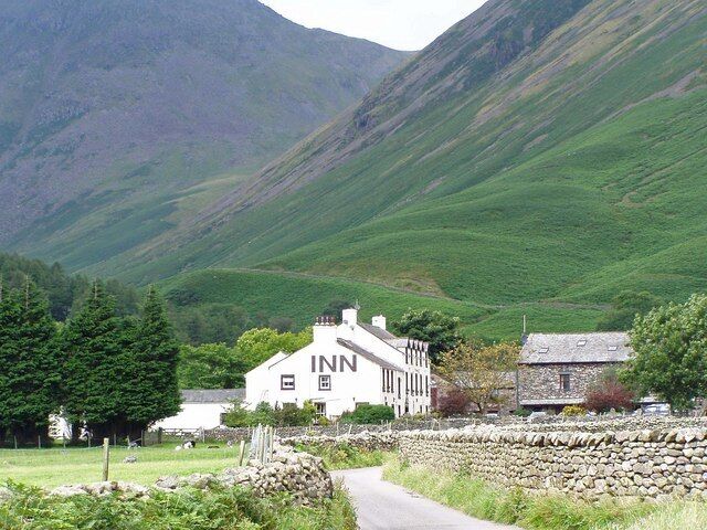 A white building labeled 'INN' in a rural setting with green hills in the background.