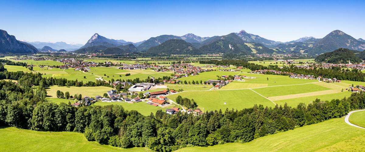 A mountainous landscape with a village nestled among green fields and forests.