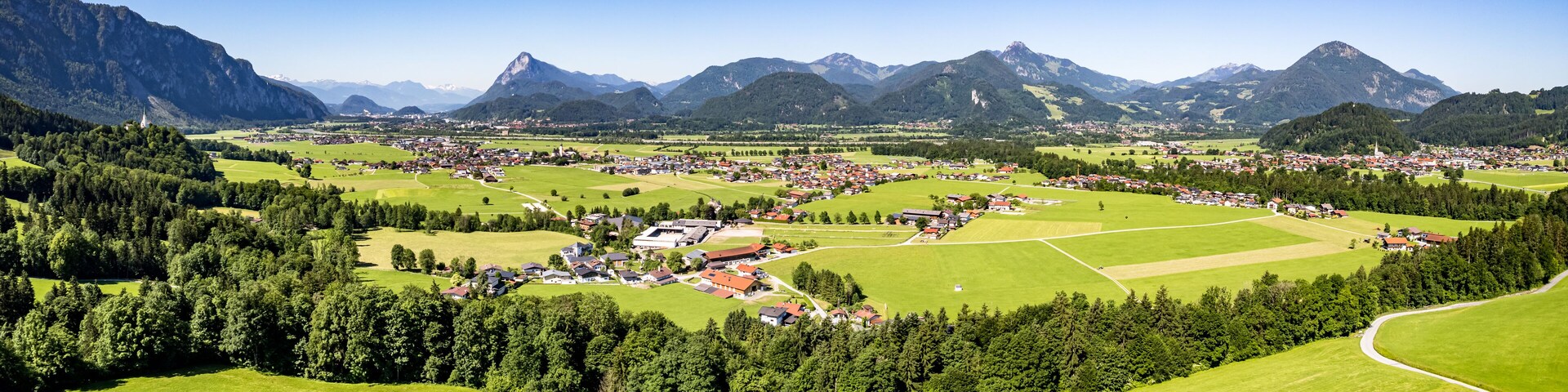 A mountainous landscape with a village nestled among green fields and forests.