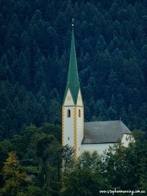 A fairytale church sits high on the hilltop overlooking the tiny village far below.
Timber houses with steeply pitched roofs, balconies with window shutters open wide. Flowering geraniums spilling from planter boxes like pink and red waterfalls cascading to the ground. Beyond dark green fir trees march like soldiers up the mountain in an attempt reach the sky. Austria you are ridiculously beautiful more than my simple words can describe.