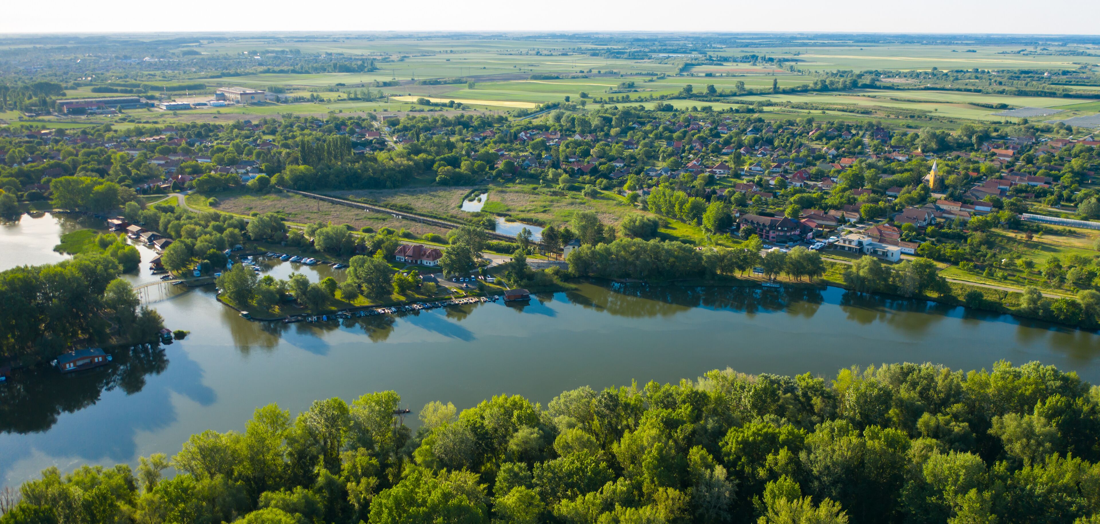 A river winding through a town with houses and greenery.