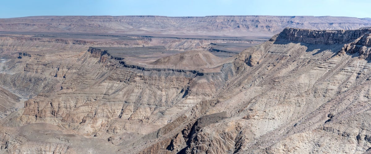 A vast canyon with layered rock formations and a river running through it.