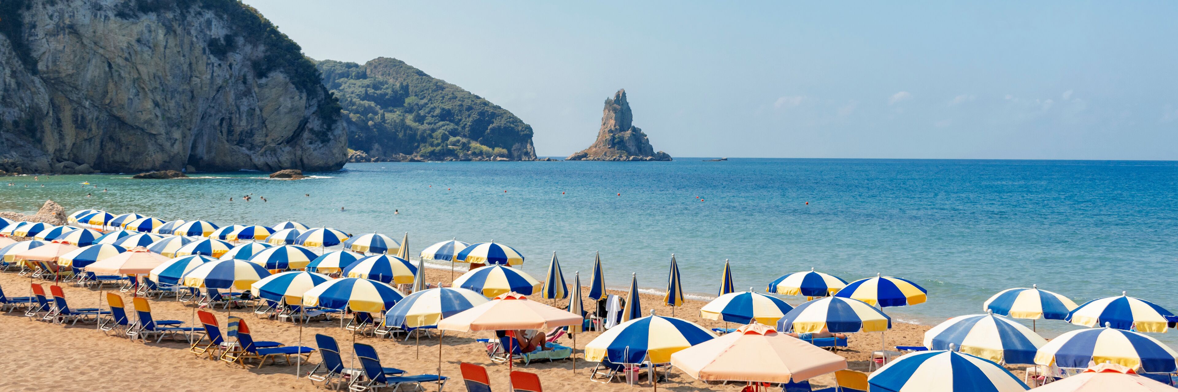 A beach with numerous blue and white striped umbrellas and sun loungers.