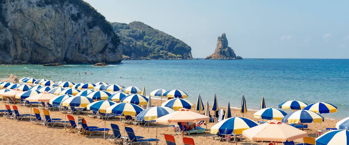 A beach with numerous blue and white striped umbrellas and sun loungers.