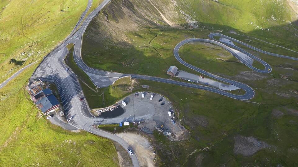 An aerial view of a complex road interchange surrounded by green hills.