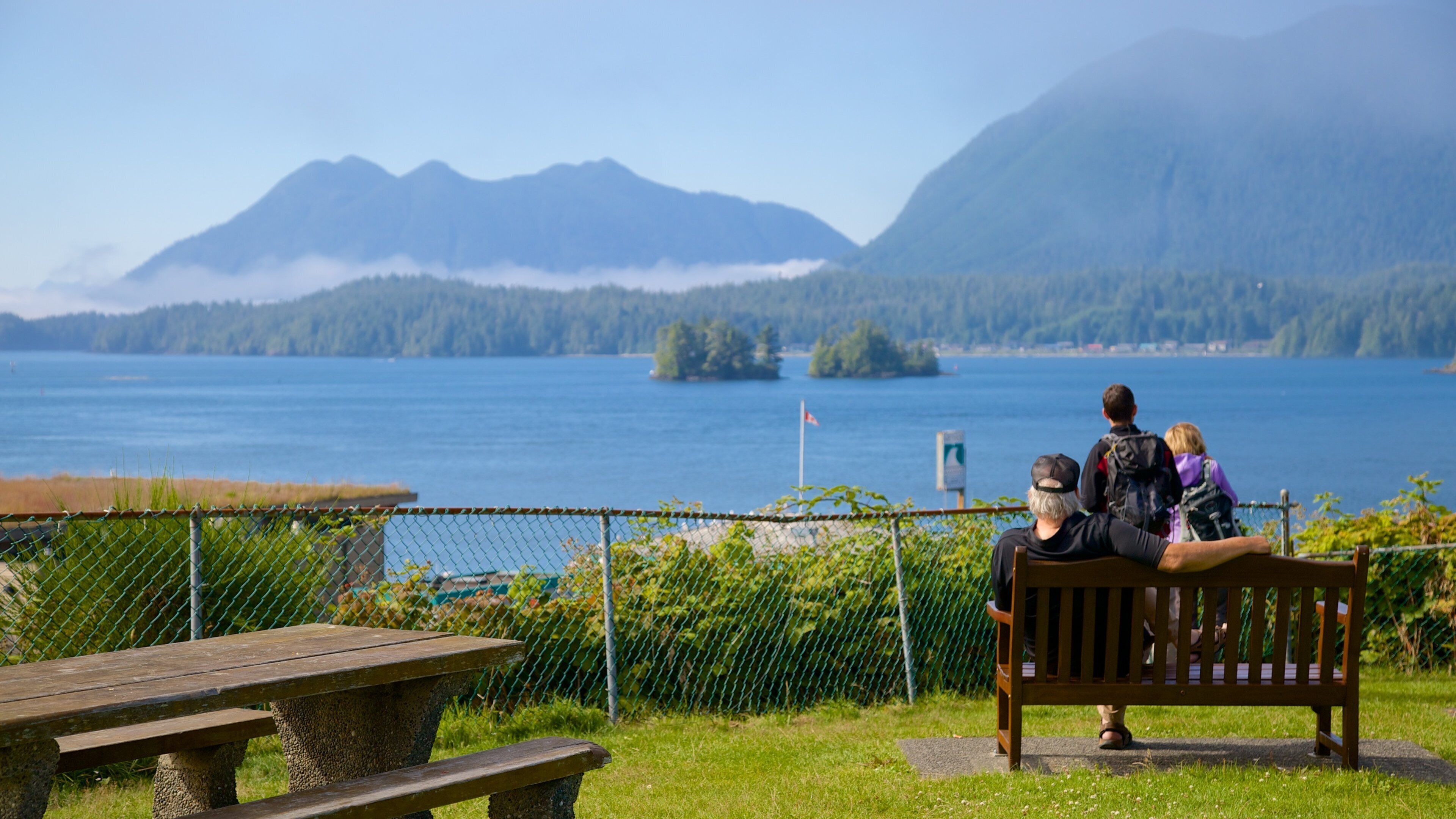 A bench overlooking a lake with mountains in the background.