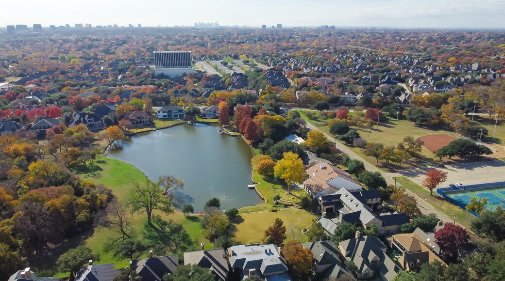 Aerial view lakeside houses with vibrant fall foliage and downtown Dallas, Texas in background, Park Central upscale waterfront suburban residential homes mature trees, upper class neighborhood