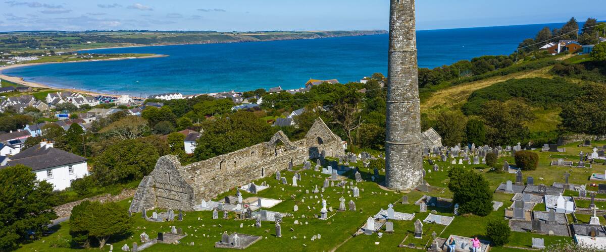 A coastal town with a prominent stone tower, a historic church, and a cemetery.
