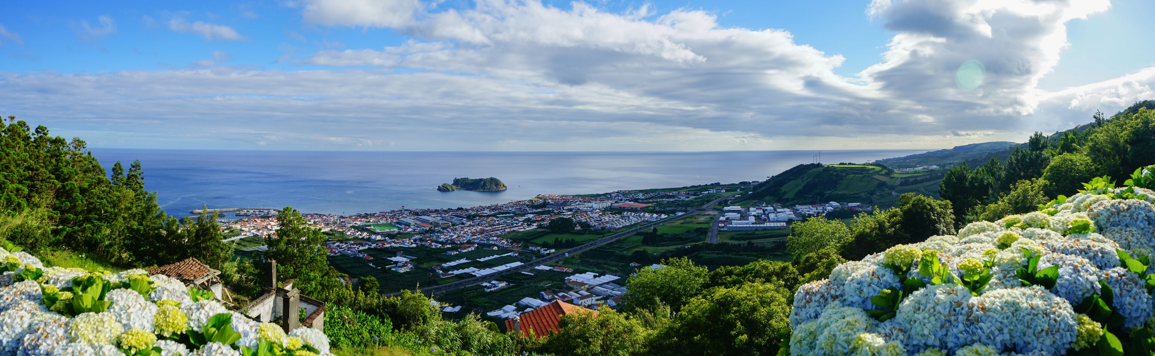A coastal town with a small island, lush greenery, and a clear sky.
