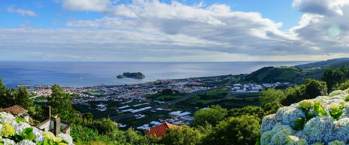 A coastal town with a small island, lush greenery, and a clear sky.