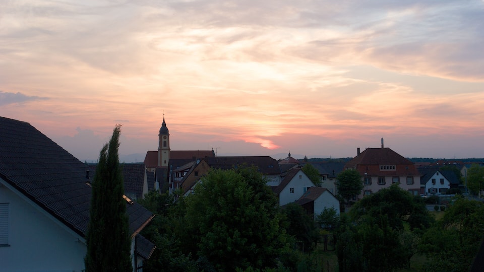 A sunset over a town with houses and a church.