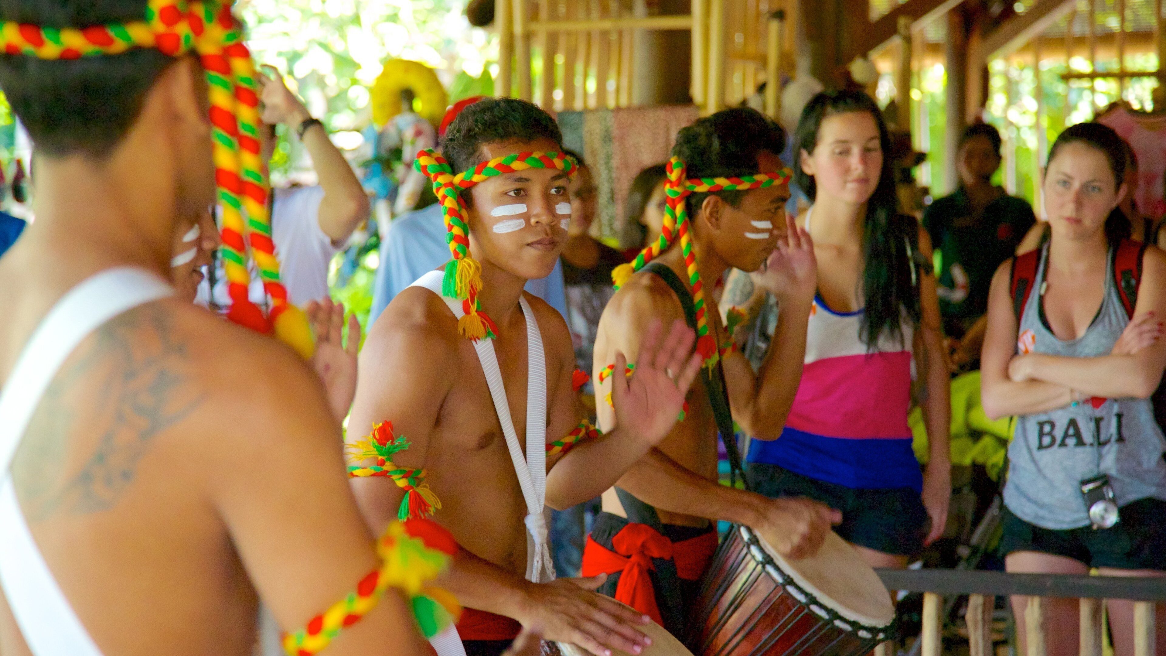 A group of people in traditional attire with colorful headdresses, playing drums.